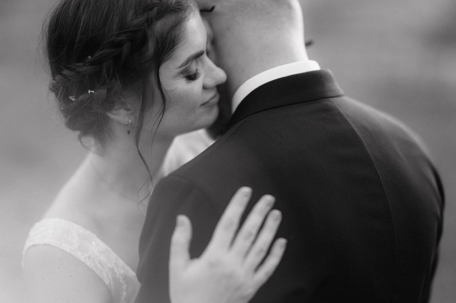 Black and white intimate wedding portrait showing couple embracing in romantic moment during photoshoot.