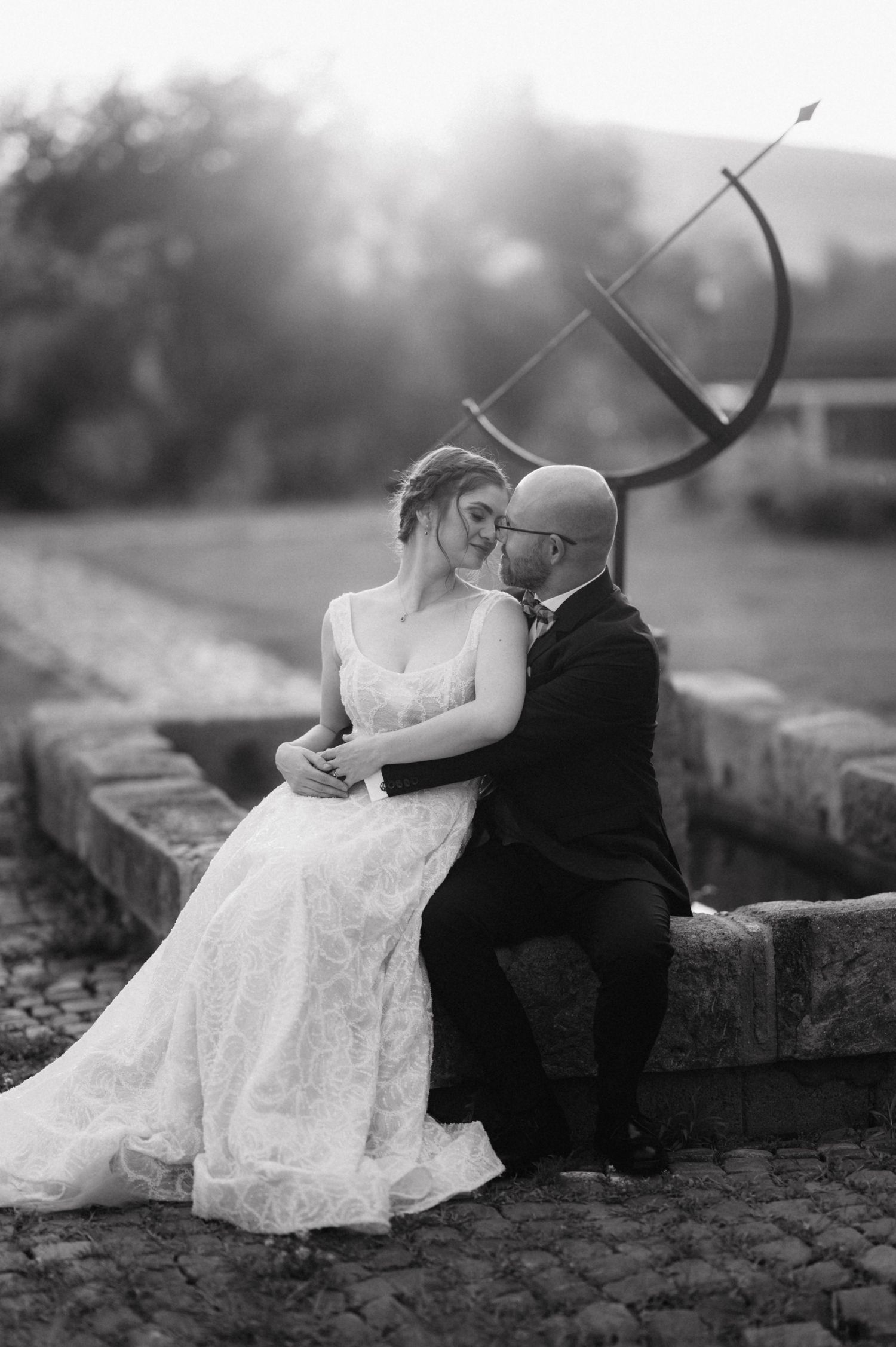 Black and white wedding photographs show tender moments between newlyweds seated on stone steps outdoors.