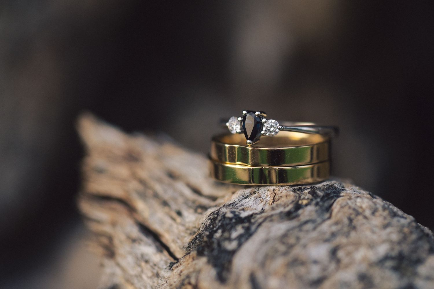 Wedding rings displayed on natural wood texture with shallow depth of field.
