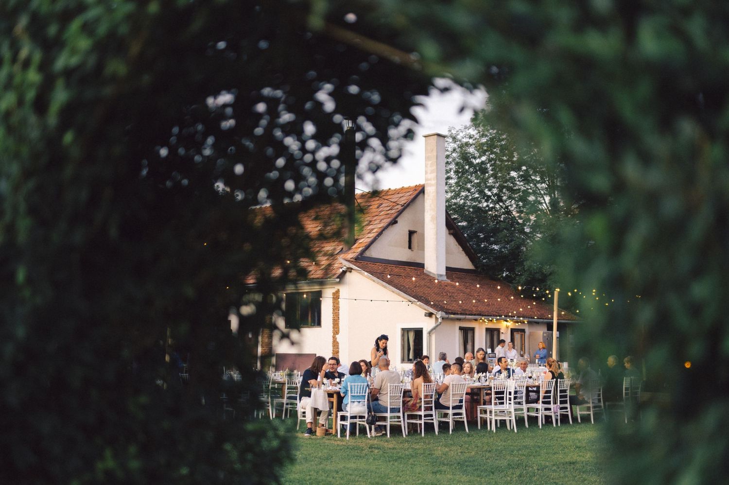 White chairs arranged for an outdoor wedding reception at a rustic farmhouse venue.