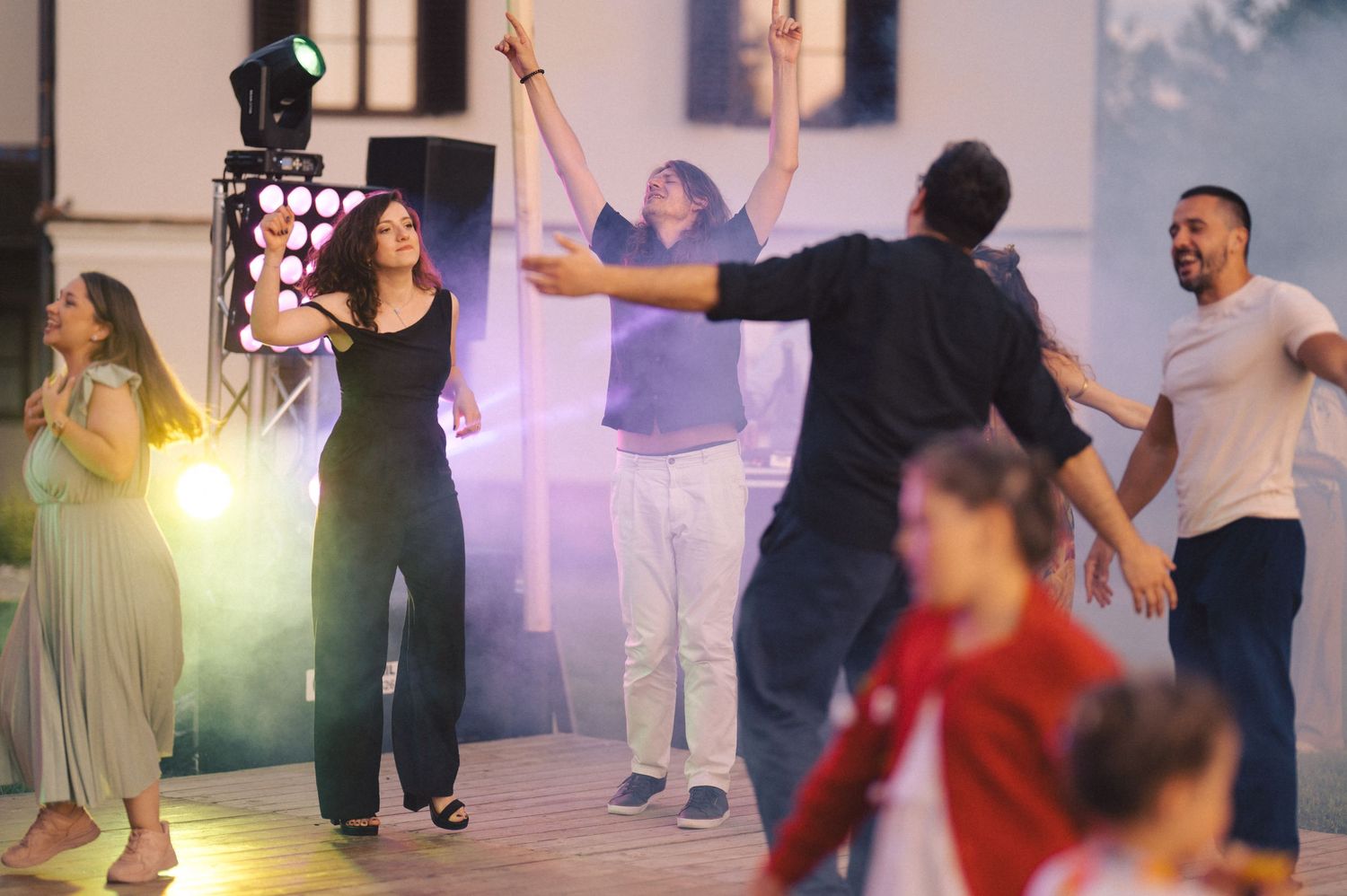 People dancing together in a group class with colorful lighting in a studio setting.