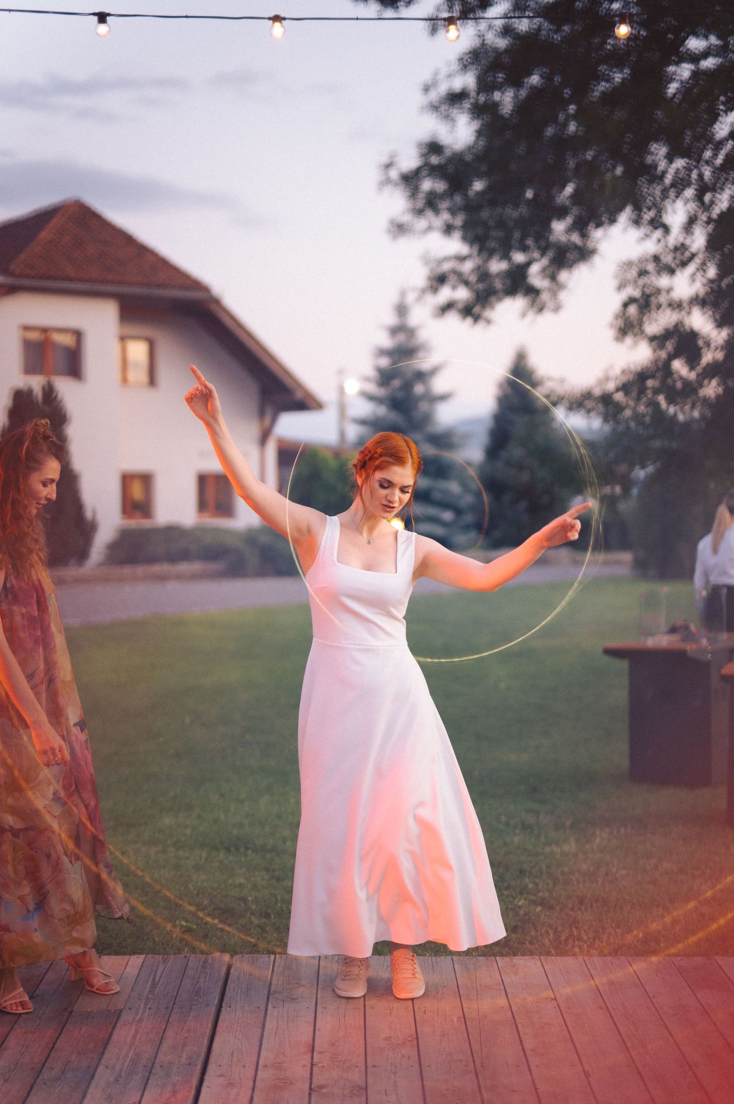 A white dress spinning in motion at sunset against a backdrop of a house and lawn.