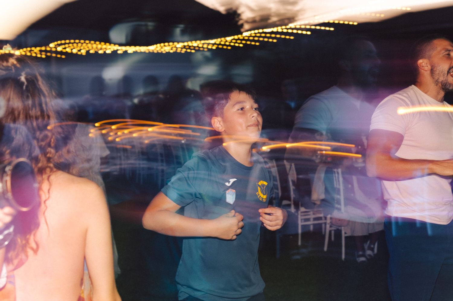 A person dances in a dimly lit room with motion blur and light trails creating a dynamic nightlife atmosphere.
