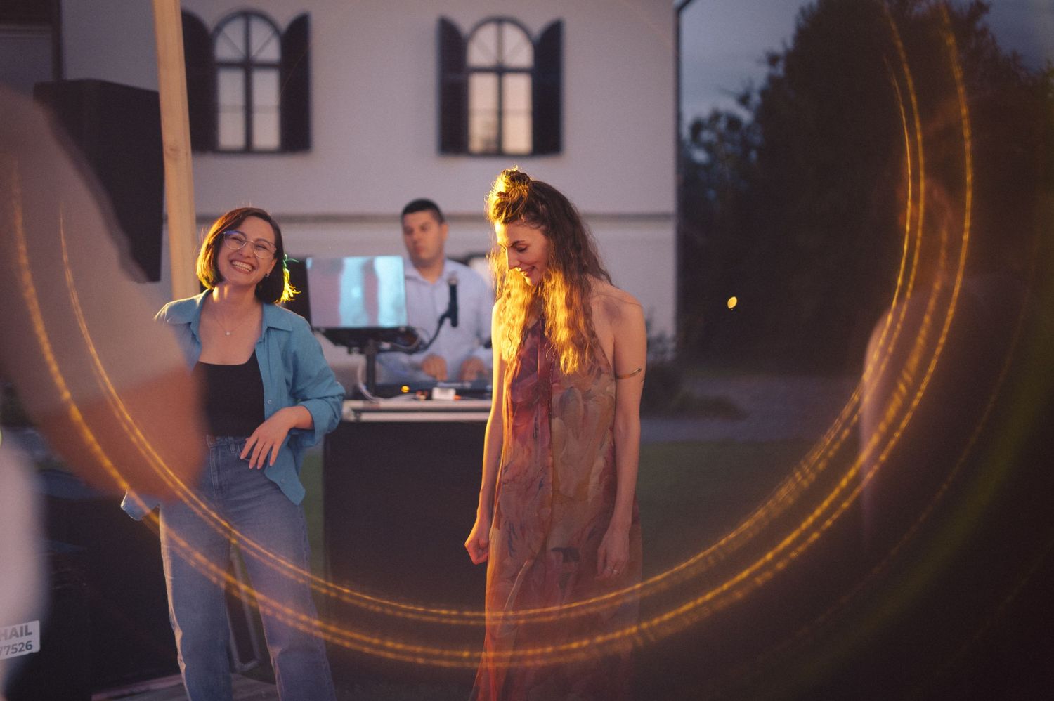 Outdoor evening gathering with warm lens flare effects creating a golden circular glow.