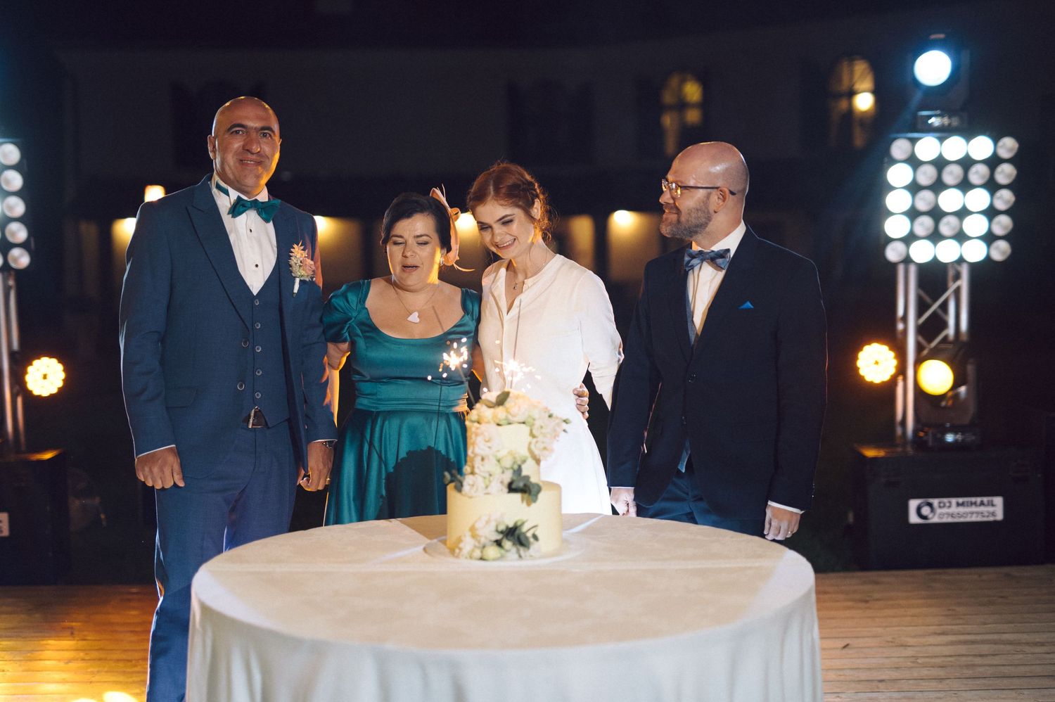 Wedding party poses at night under string lights on outdoor patio for formal group photo.