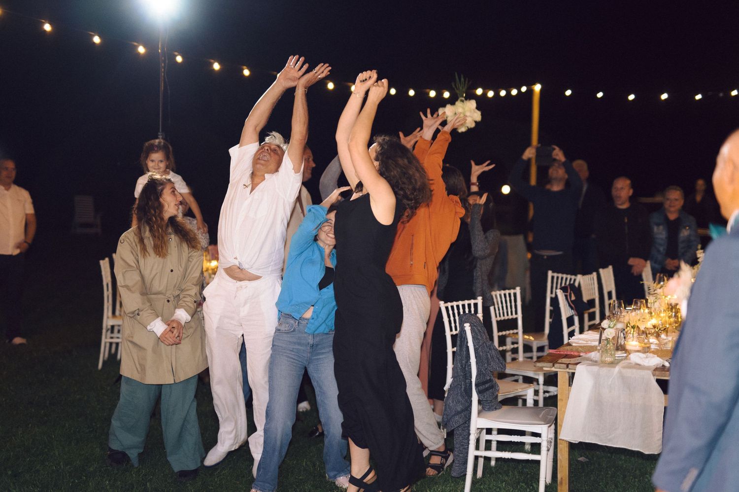 People enjoying a festive outdoor party at night with string lights illuminating the dance area.