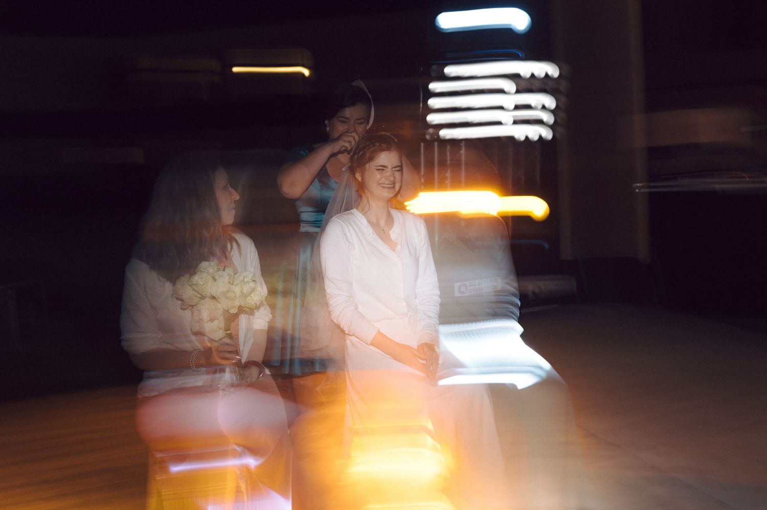 Long exposure photo of people moving through a dark space creating light trails and ghostly motion blur effects.