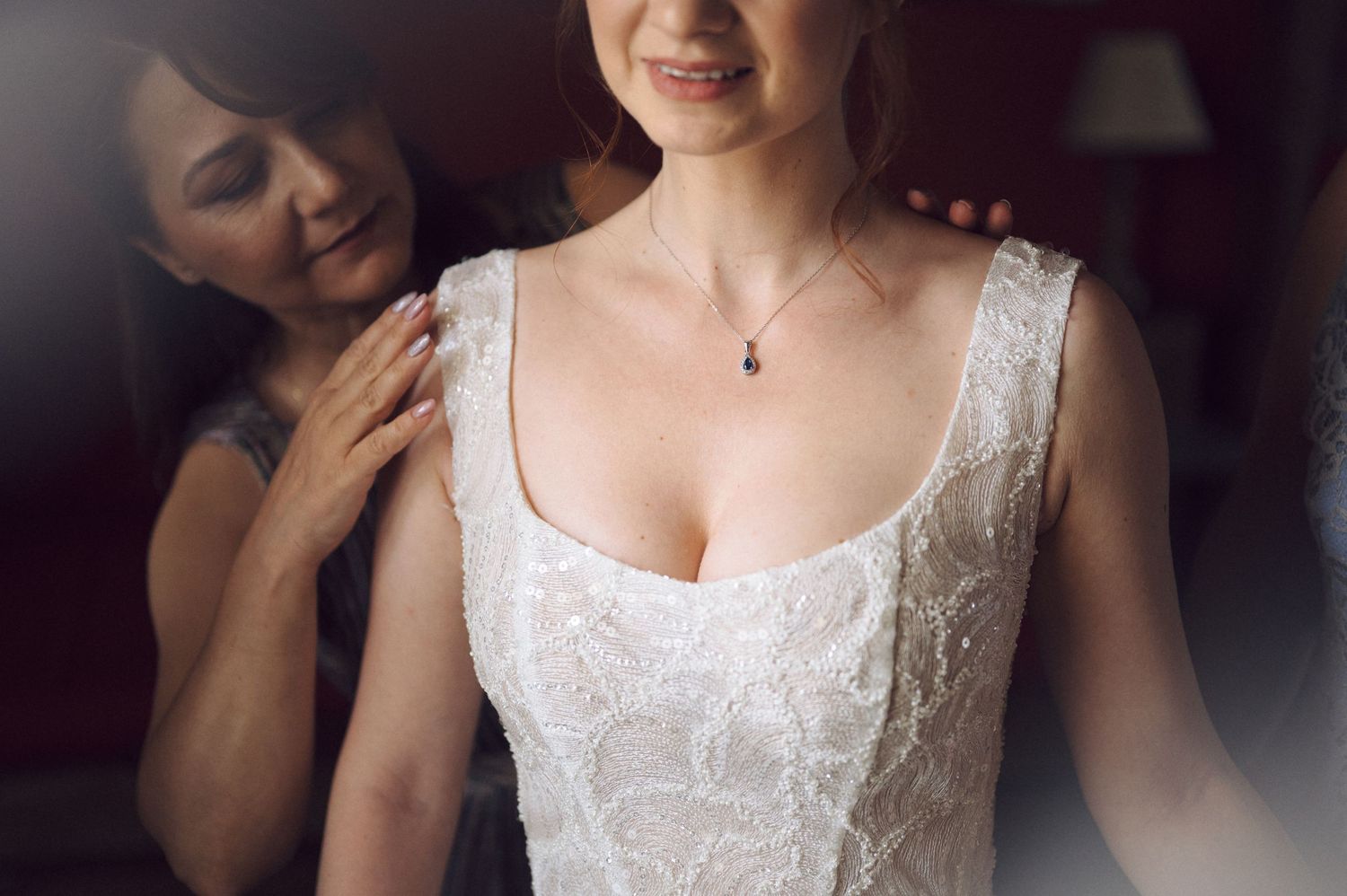 A close-up of an elegant white lace wedding dress being fitted, with soft lighting creating a romantic atmosphere.