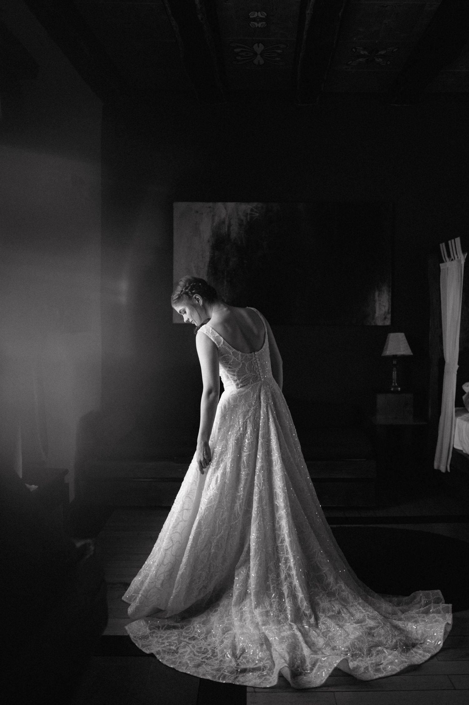 A series of black and white photographs showing a flowing lace wedding gown displayed in dramatic lighting.