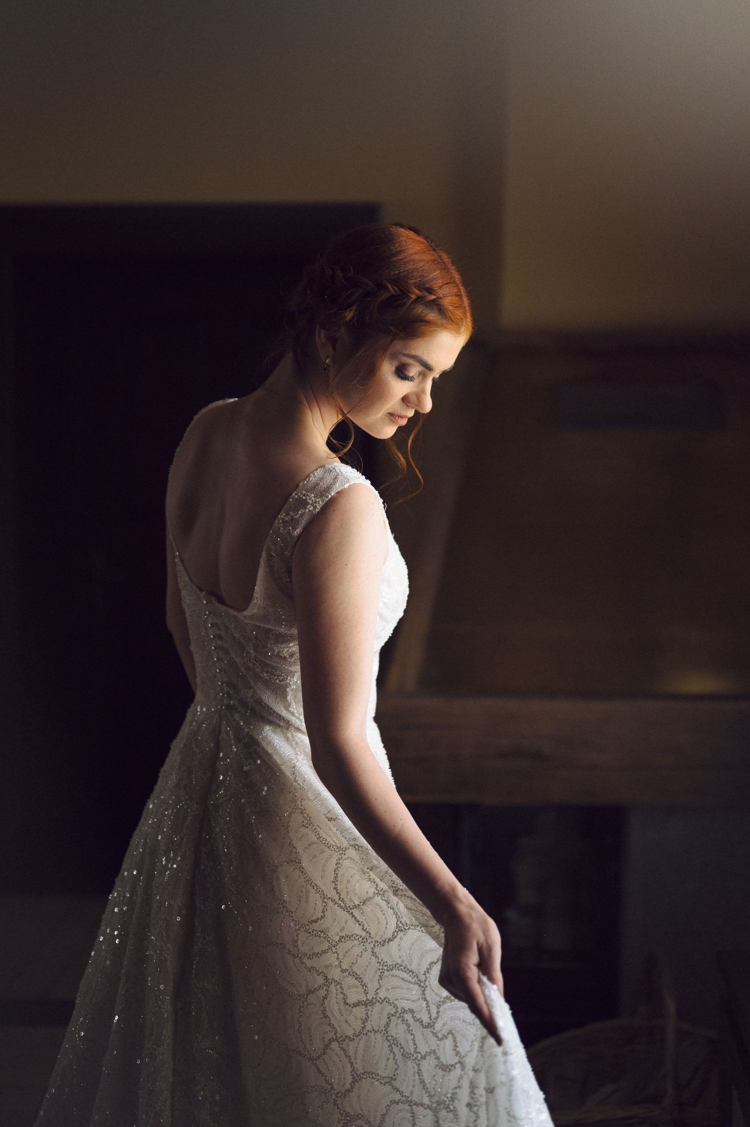 A woman in a sparkly white ballgown stands in dramatic lighting creating a romantic silhouette.