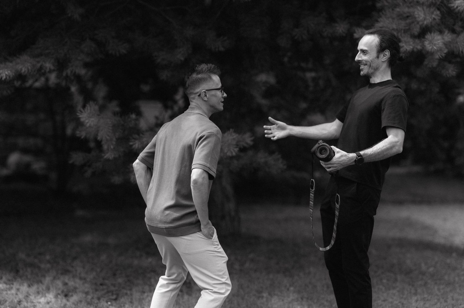 Two golfers conversing on a golf course while practicing their putting technique in black and white.