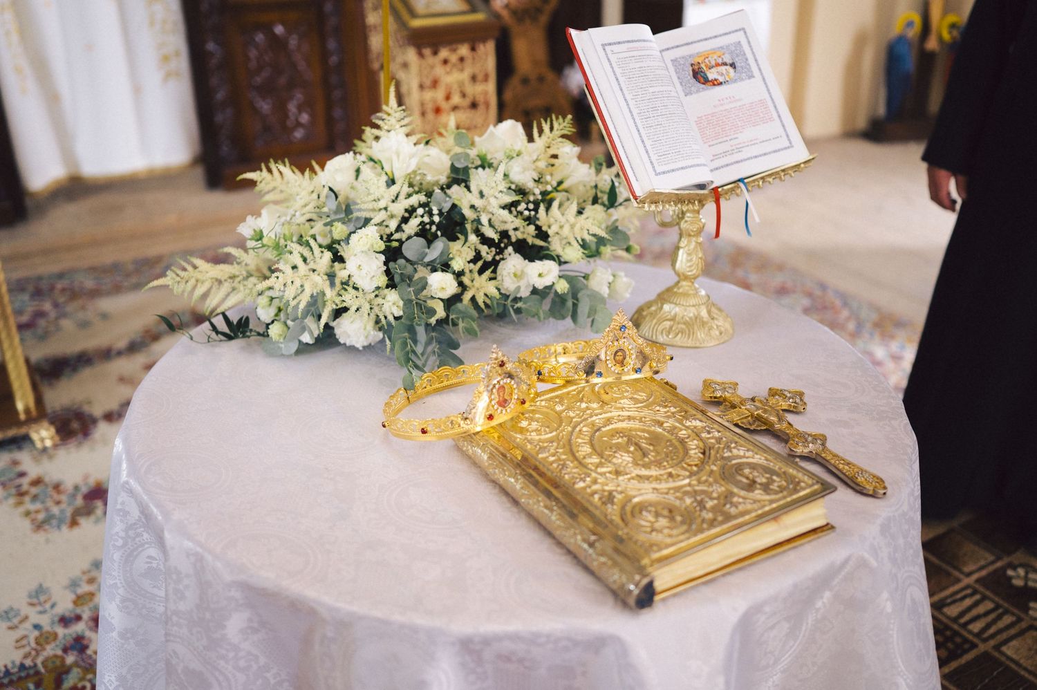 A golden mirrored serving tray sits alongside white floral arrangements at an elegant wedding reception table.