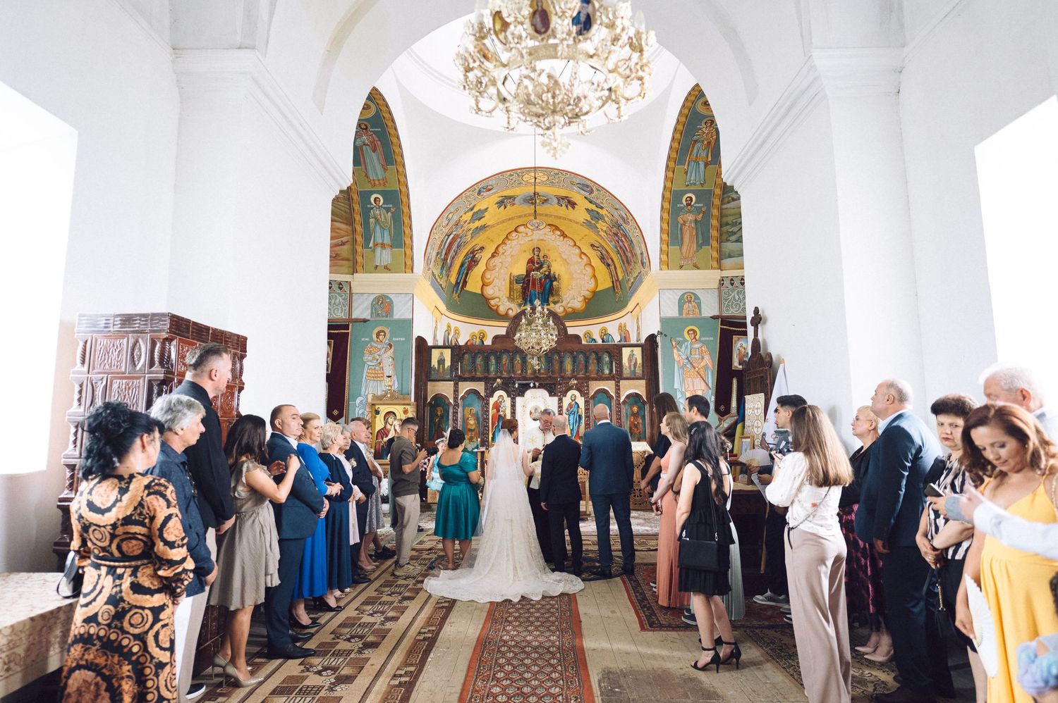 A panoramic view of a traditional church wedding ceremony with guests lining the aisle and an ornate altar backdrop.