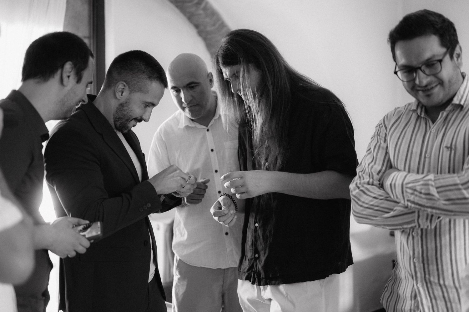 A group of people gather around to examine something together in black and white photograph.