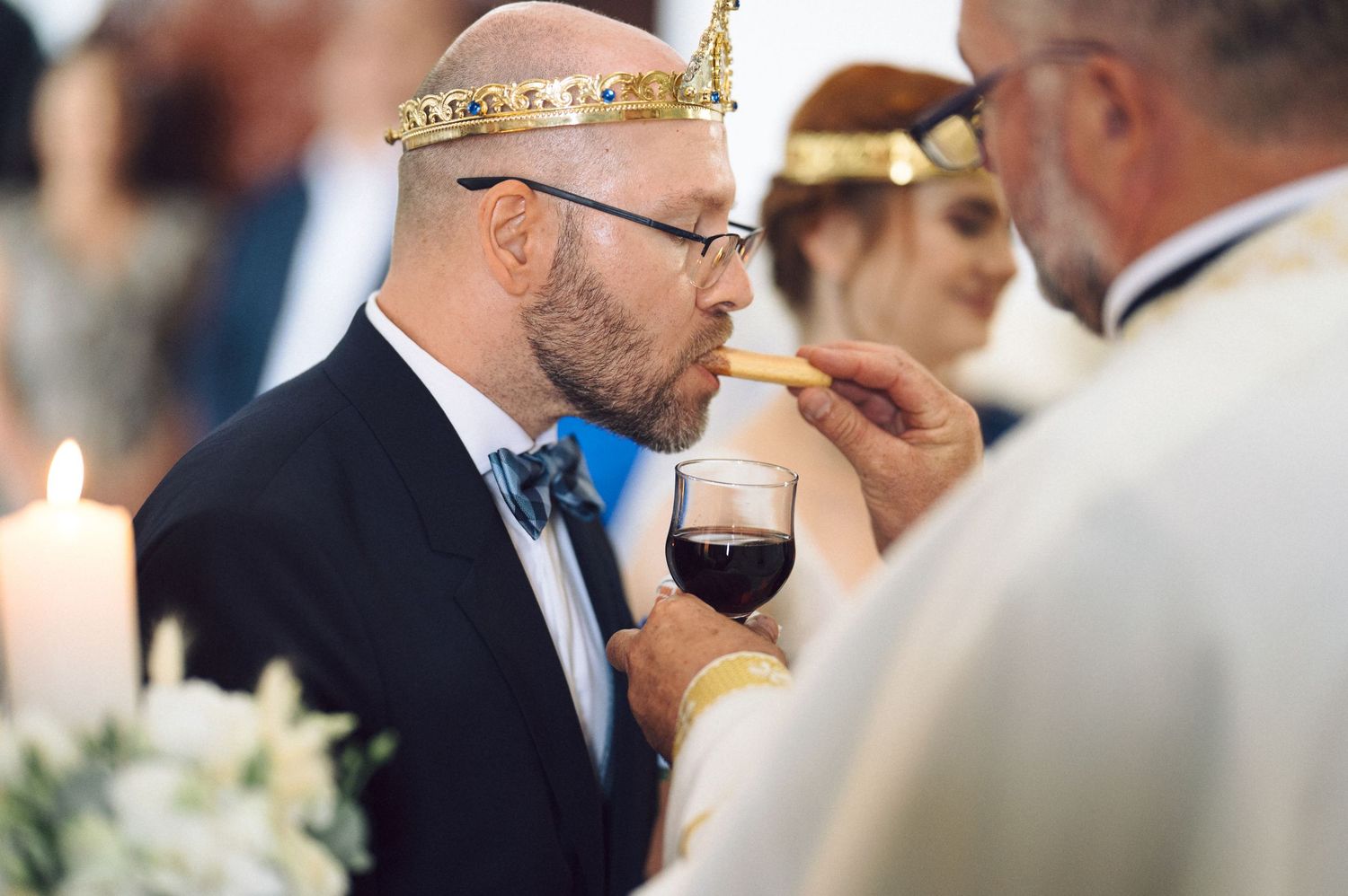 Wedding guests gathered at an elegant reception toast and enjoy red wine while socializing at banquet tables.