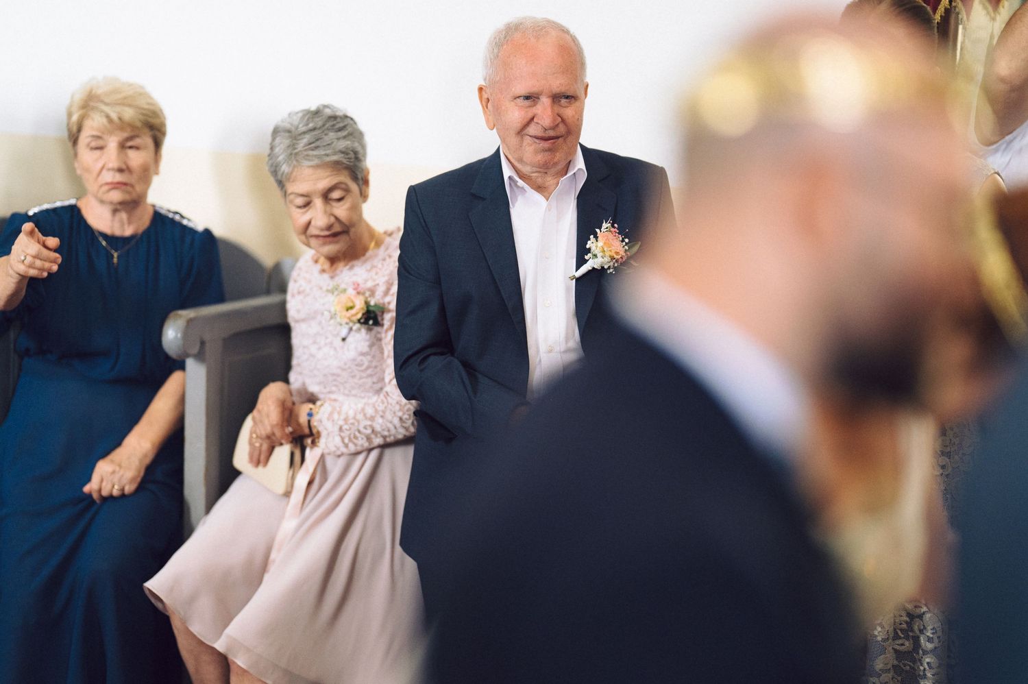 Two women in formal dresses and a man in a suit attend an elegant occasion together at an outdoor venue.