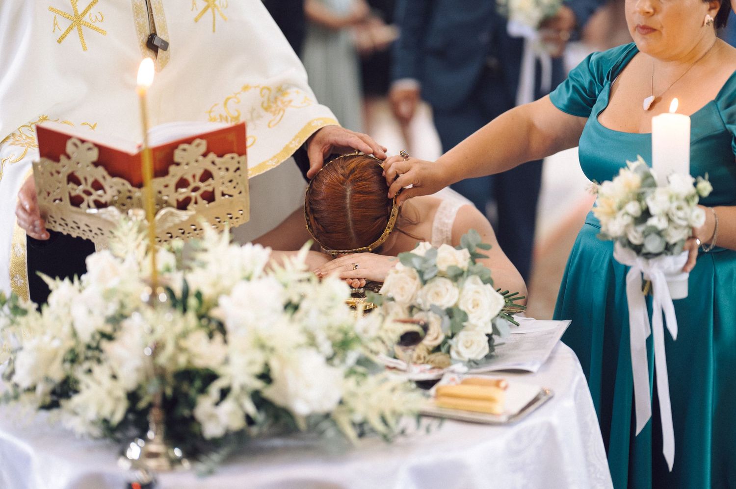Wedding guests in teal dresses enjoy an elegant dinner reception with white floral centerpieces.