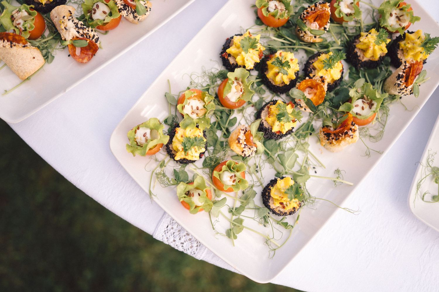 Colorful appetizer platters of stuffed mushrooms garnished with fresh herbs and seasonings on white serving trays.