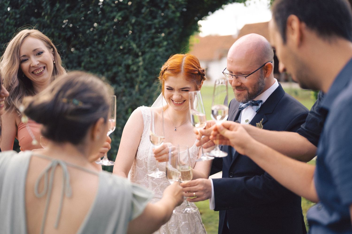 A group of people raising wine glasses together for a celebratory toast at an outdoor wedding reception.