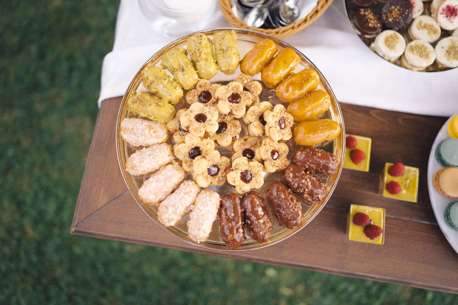 Overhead view of an elegantly arranged platter with assorted cookies and pastries on a wooden serving tray.