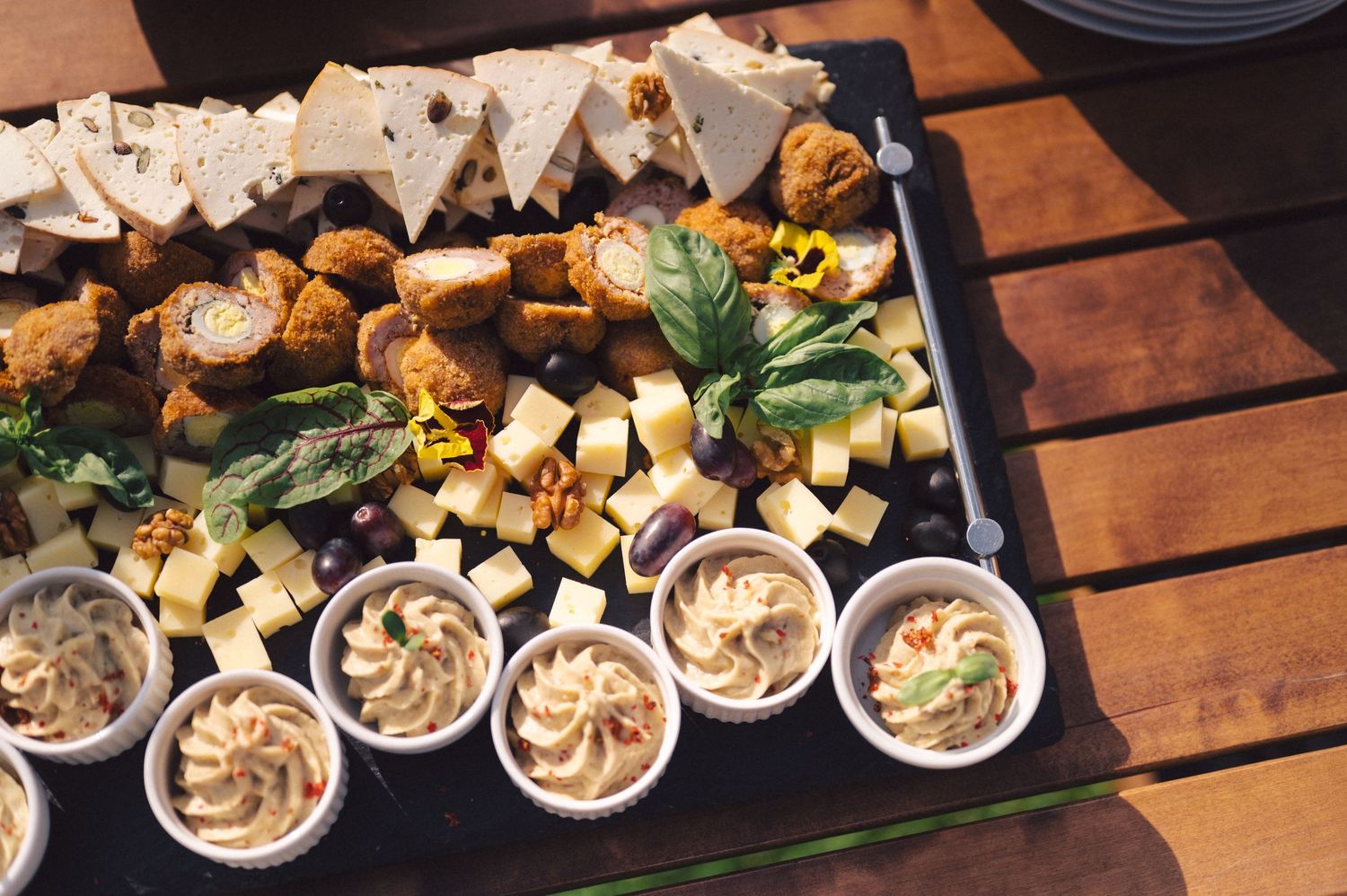 Mini tarts with mousse filling and garnishes are elegantly arranged on dark platters for an upscale catering event.