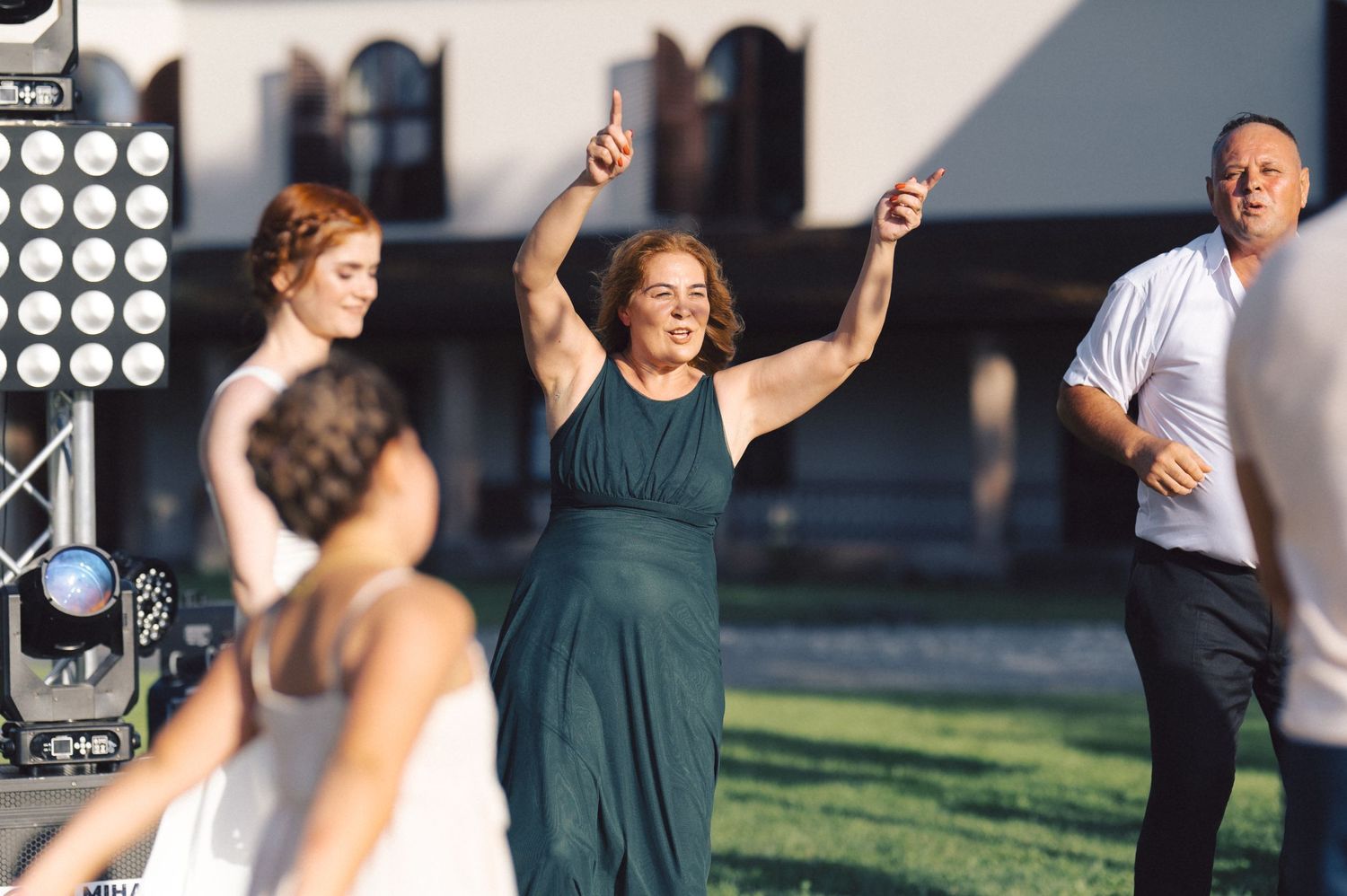 Group of dancers performing together outdoors on a summer day, raising their arms in synchronized motion.