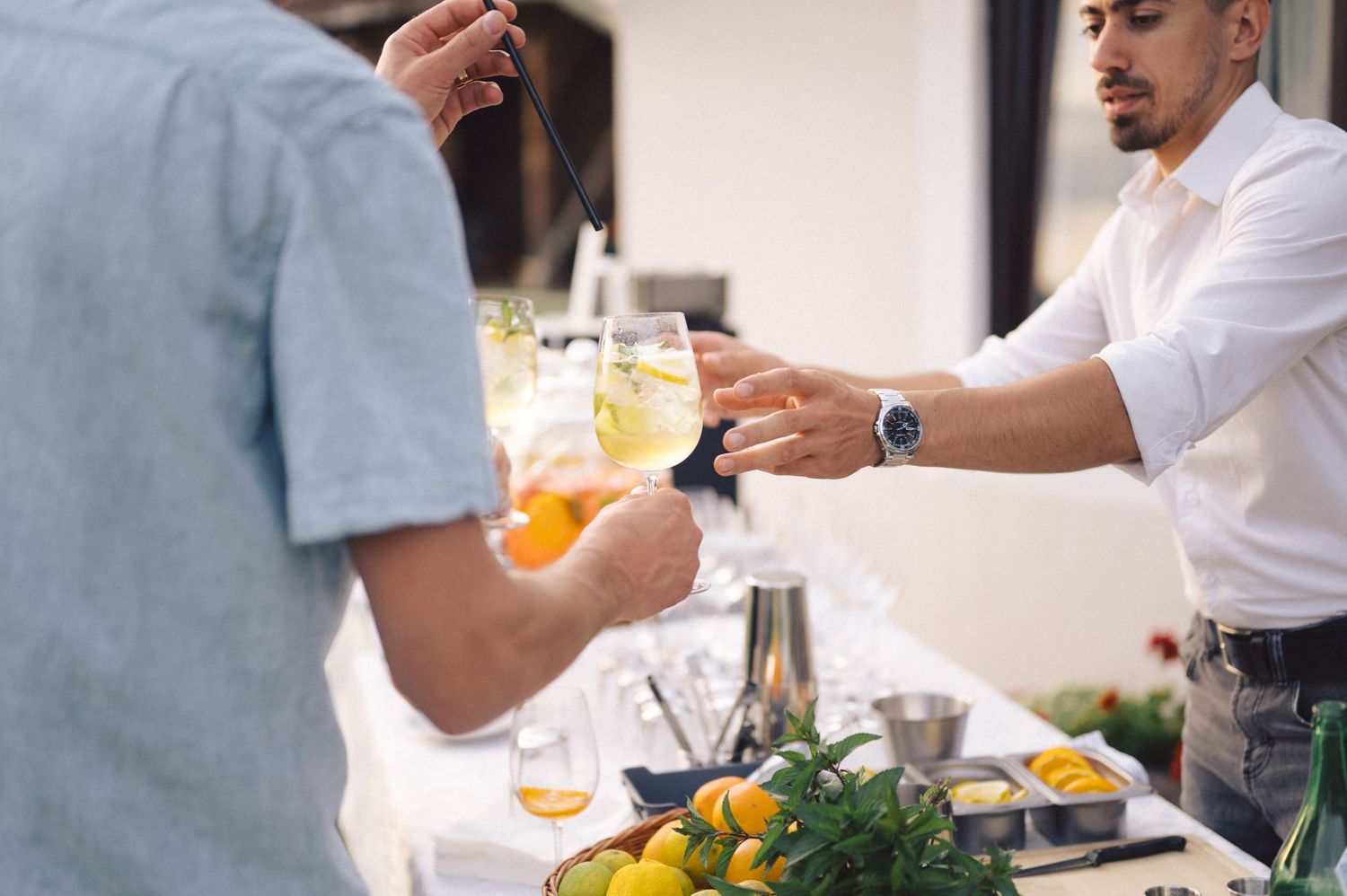 Casual diners at a waterfront restaurant enjoy beverages and conversation with friends during a sunny afternoon.