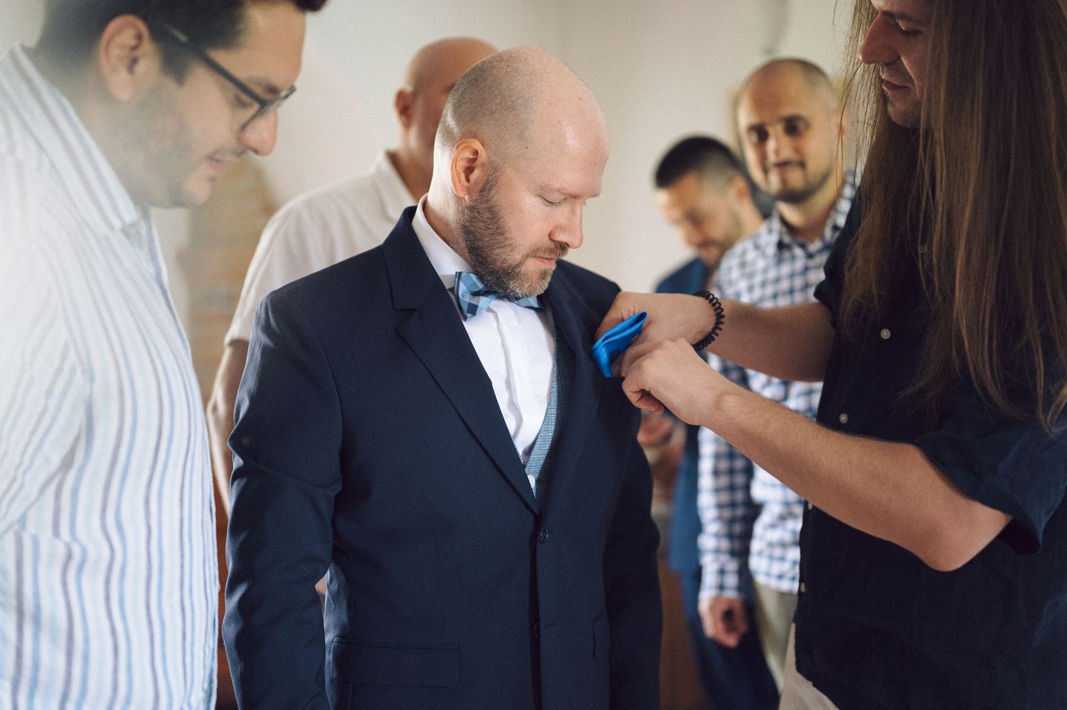 People help with final adjustments to a suit as they prepare for a formal occasion.
