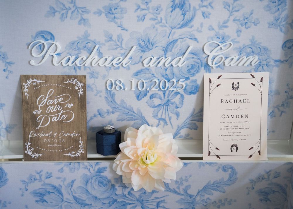 Wedding details with floral decor and invitation suite featuring the text 'Rachael and Cam' on blue background.
