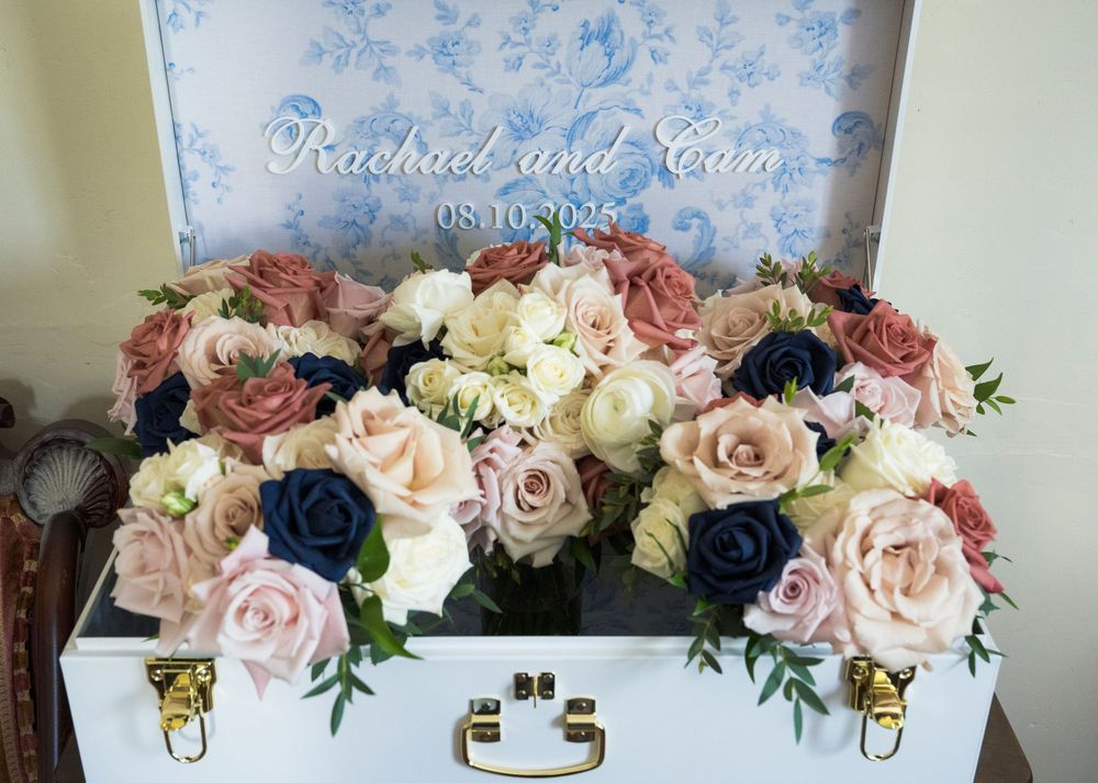 Elegant wedding floral arrangement featuring pink, white and navy roses in a decorative box.