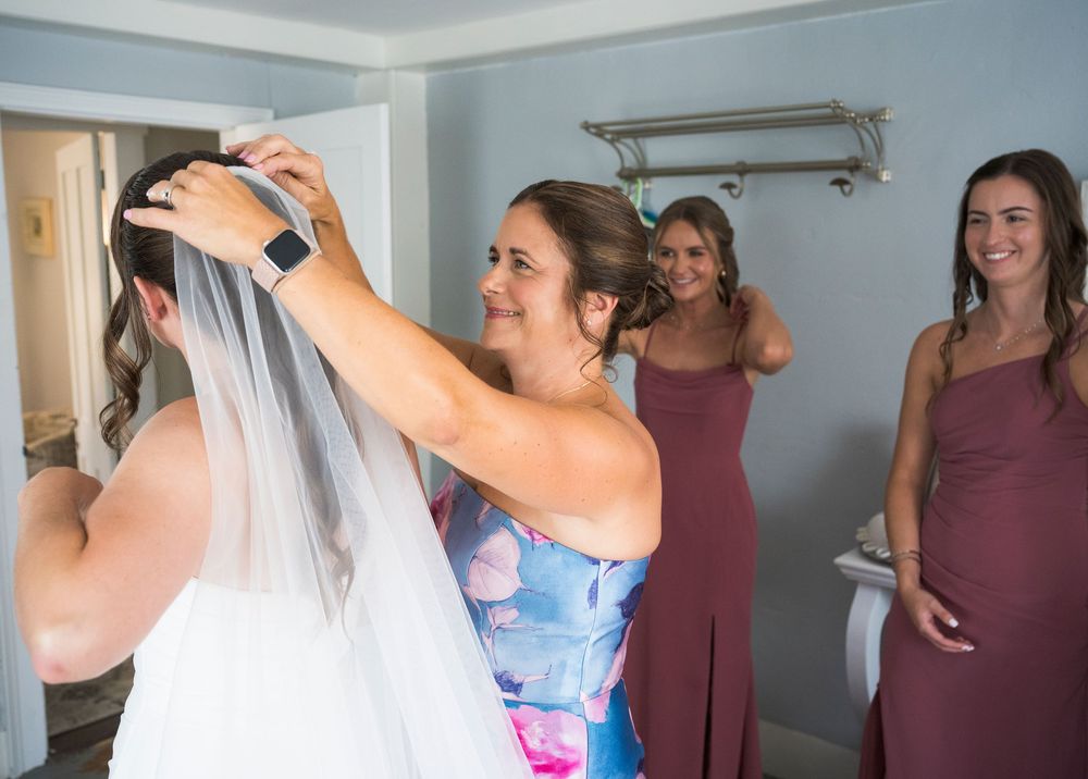 Wedding preparations in a room with people in mauve dresses.