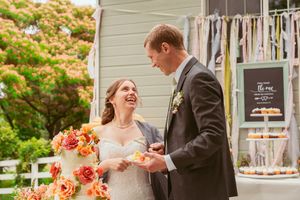 A joyful moment between newlyweds in front of a decorated wedding backdrop with streaming ribbons.