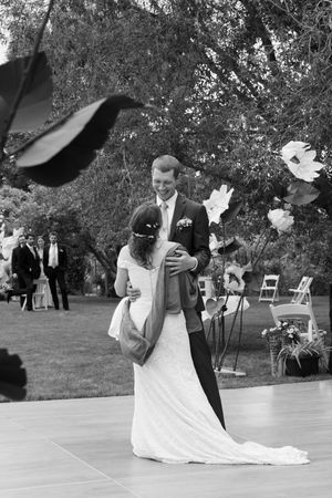 Couple sharing a romantic dance moment on an outdoor dance floor surrounded by trees and guests.