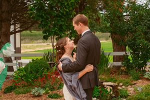 A romantic moment between a couple in formal attire against a garden backdrop.