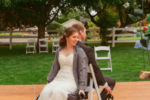 Couple sharing tender moment while seated on outdoor wooden dance floor.