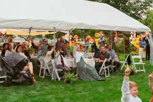 Wedding guests seated under a white tent enjoying an outdoor celebration.