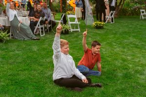 People dance joyfully on a grassy lawn during an outdoor celebration event in the summer.