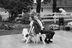 Couple engaged in an intimate slow dance outdoors during golden hour with guests seated nearby.