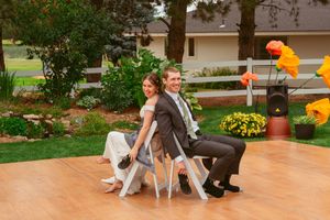 Dancers performing energetic moves on a wooden dance floor at an outdoor wedding reception.