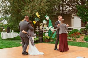 Couples dancing at an outdoor wedding reception with decorative lighting and floral arrangements.