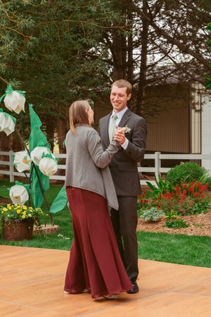 Couple enjoying their first dance together outdoors on a wooden deck with festive decorations.
