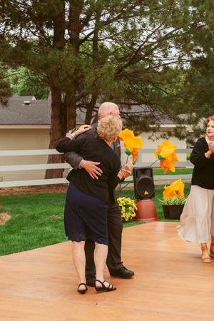 A couple dancing together during a first dance at an outdoor wedding reception on a wooden dance floor.