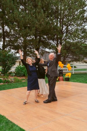 Group of guests dancing with raised arms on outdoor patio during celebration.