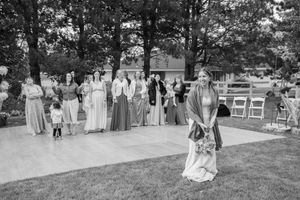 Black and white photo of wedding guests gathered on a patio during an outdoor ceremony.