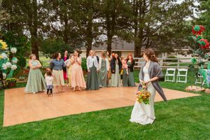 Wedding guests gather on a lawn decorated with vintage mint green chairs and pastel accents for an outdoor ceremony.