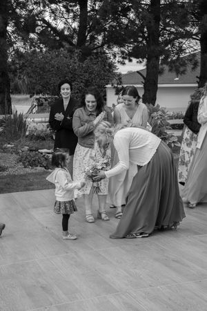 Black and white vintage photography shows people gathering at an outdoor event on a paved patio area in formal attire.
