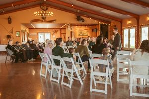 Rows of white folding chairs set up in a wooden lodge-style venue with natural light streaming through windows.