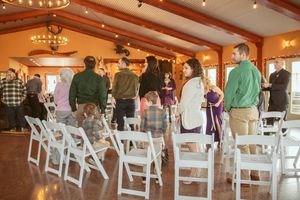 White folding chairs arranged in rows for a ceremony inside an elegant wood-paneled room with glowing chandeliers.