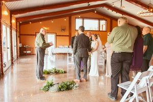 A panoramic indoor venue with white chairs set up for a formal event and guests gathering in the background.