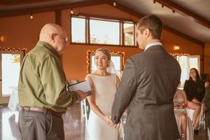 Wedding guests mingle and chat during a reception event in a warm-lit rustic barn venue.